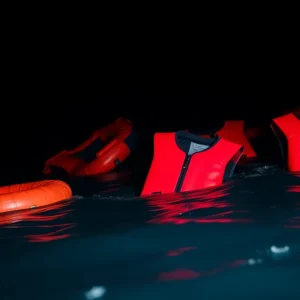 Life jackets in the ocean representing a tragic human smuggling incident.