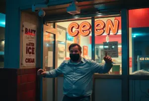 A man breaking into an ice cream shop, spilling ice cream on the floor.